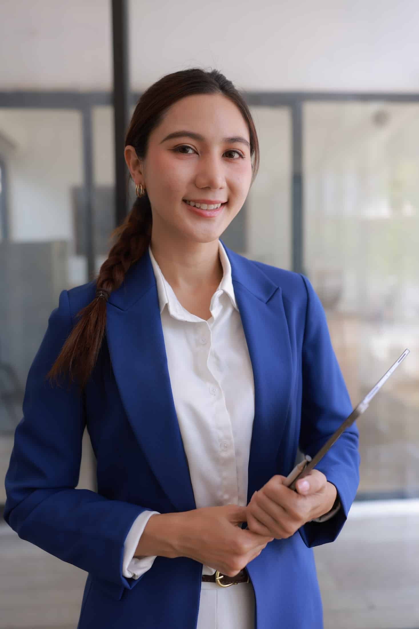 A woman in a suit sits at a desk, working on a laptop